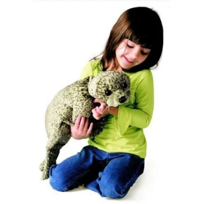 Bambina che gioca con un pupazzo a mano a forma di cucciolo di foca Bambina che gioca con un pupazzo a mano a forma di cucciolo di foca