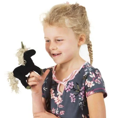 Meisje dat speelt met een zwarte mini-eenhoornvingerpop van Folkmanis